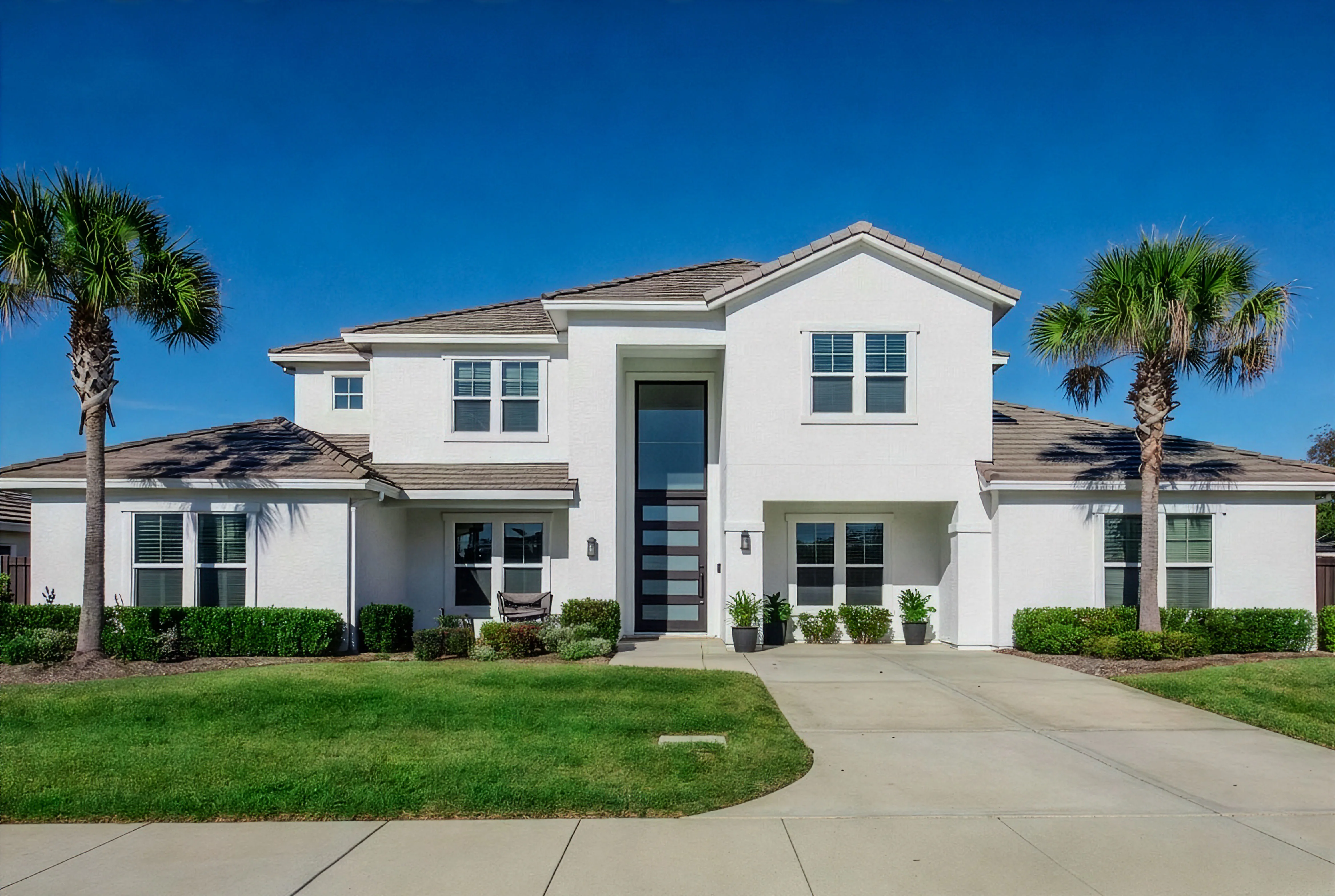 Modern white two-story Central Florida home framed by palms