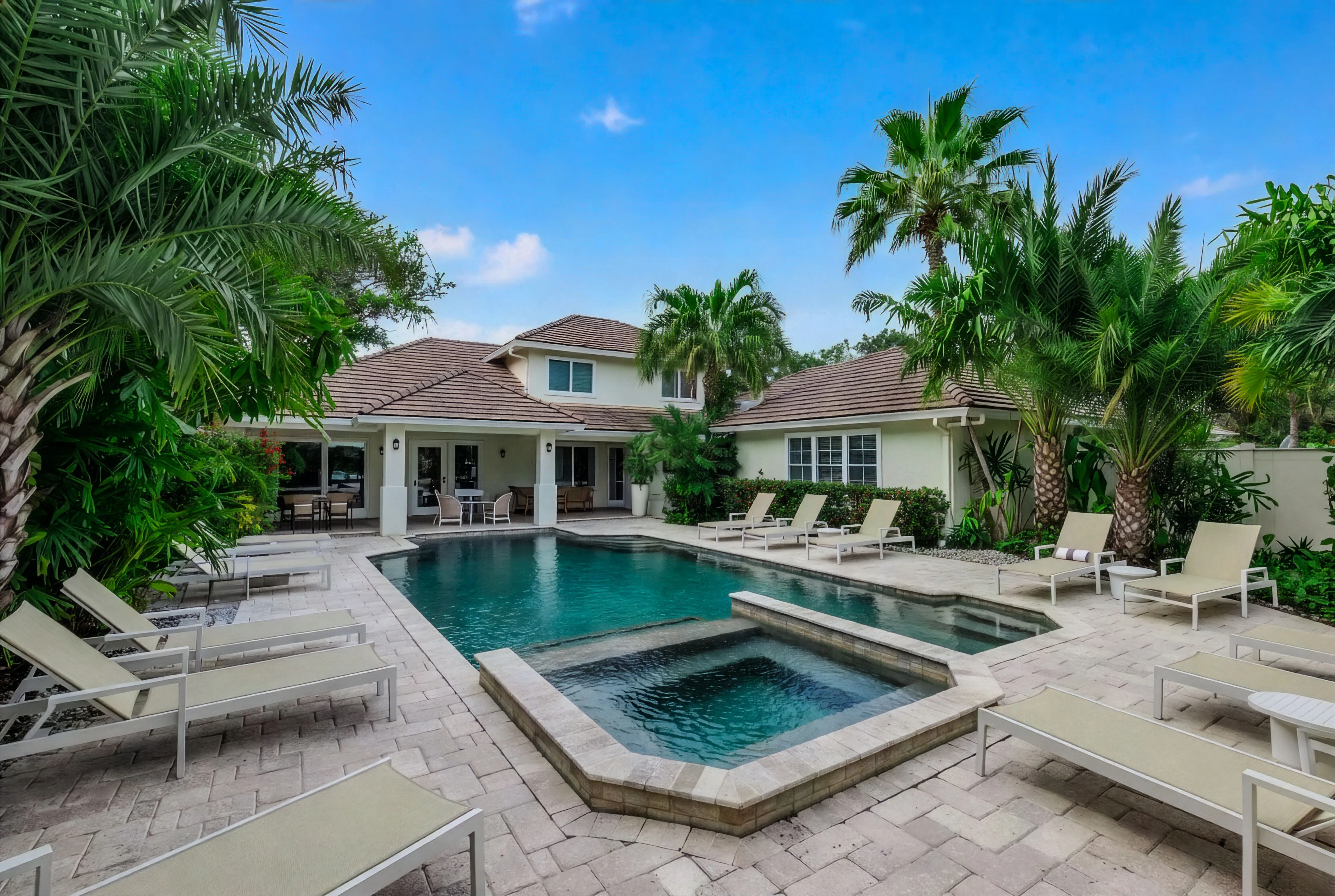 Resort-style pool and spa with lounge chairs and tropical landscaping