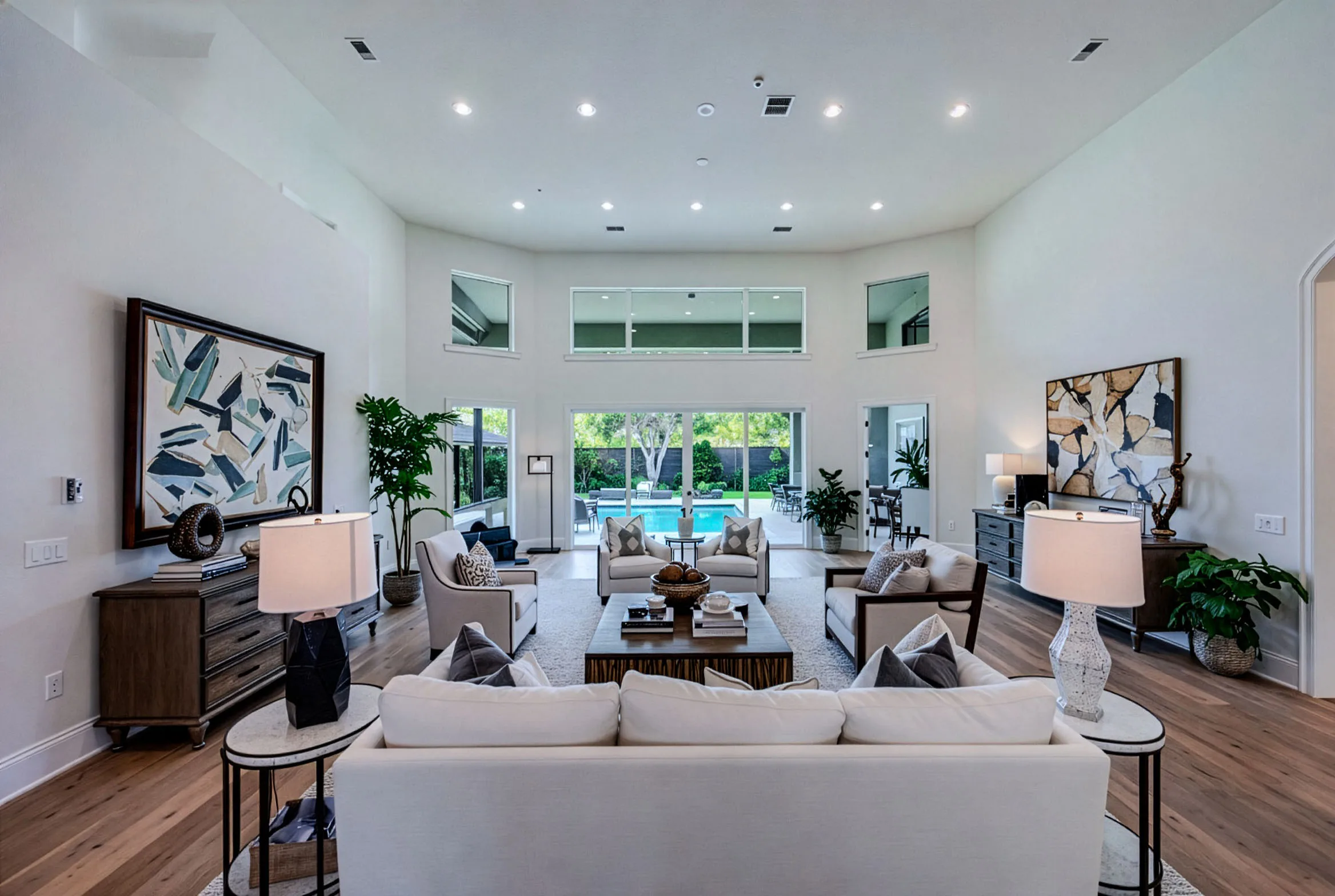 Double-height great room with modern art and sliding doors to the pool