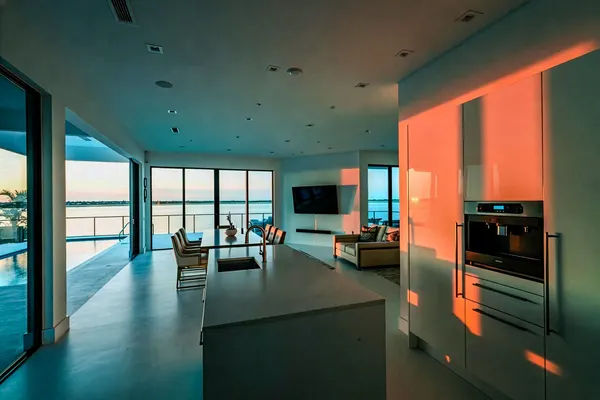 Modern open-plan kitchen and great room with waterfront sunset view
