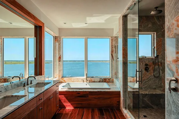 Luxury master bath with soaking tub and sweeping bay views through picture windows