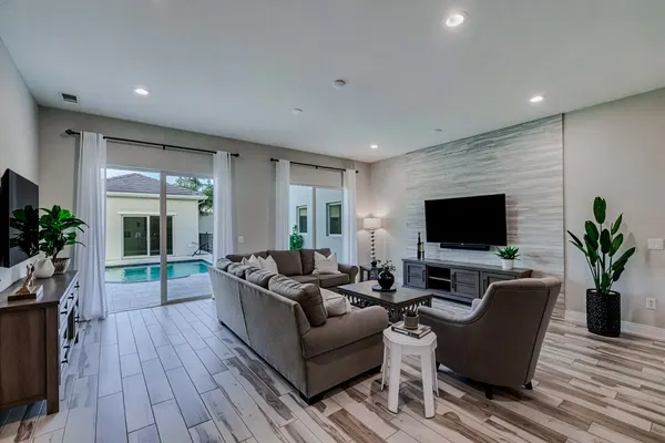Bright living room with tile flooring, TV wall and pool view