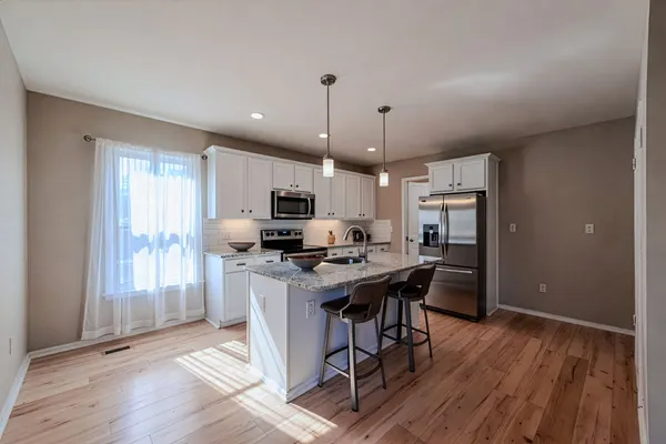 White kitchen with granite island, bar seating and natural light